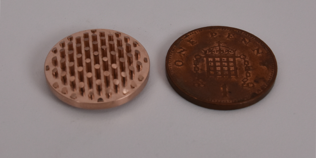 micro machined part next to a UK penny