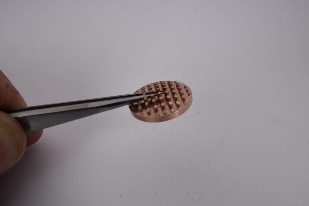 micro machined small part held in tweezers